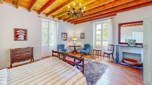 A spacious room with a wooden ceiling, a large bed, a fireplace, and two windows. - Presbytère de Pompiac (Castillonnès)