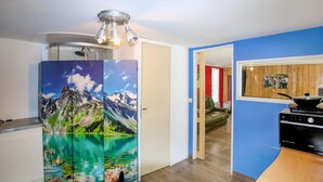 Eine Küche mit einem Herd, einem Kühlschrank mit einem Bergmotiv und einem Holzesstisch.