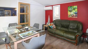 Ein Wohnzimmer mit Glastisch, einem grünen Ledersofa und einer roten Akzentwand.