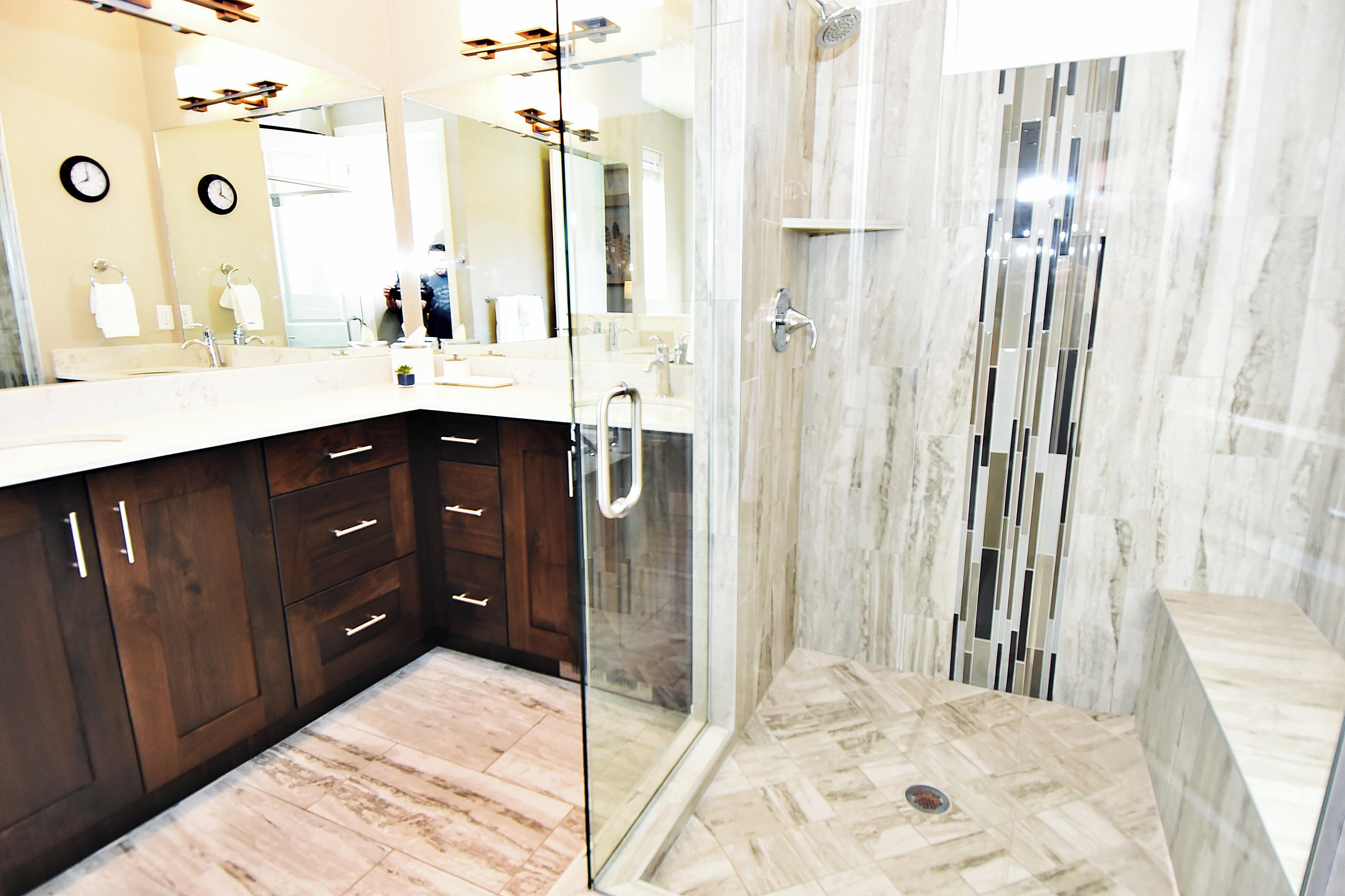A modern bathroom with a large mirror, dark wooden cabinets, and a shower area with a glass door.