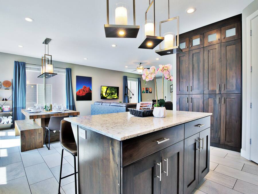 A modern kitchen with dark wood cabinets, a granite countertop, and pendant lighting.