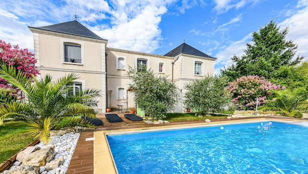 A swimming pool with a wooden deck and lounge chairs, surrounded by a garden with various plants and trees. - Beautiful home in Saint-Cyr-Sur-Loire (Saint-Cyr-Sur-Loire)