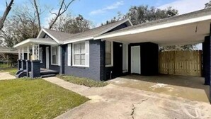 A two-story house with a covered patio and a front yard. - Tidy Apartment Near Hospital/PCC (Pensacola)