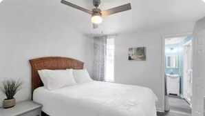 A bedroom with a bed, a nightstand, a ceiling fan, and a window with curtains. - Tidy Apartment Near Hospital/PCC (Pensacola)
