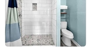 A bathroom with white tiled walls, a shower with a glass door, and a toilet with a blue wall. - Tidy Apartment Near Hospital/PCC (Pensacola)