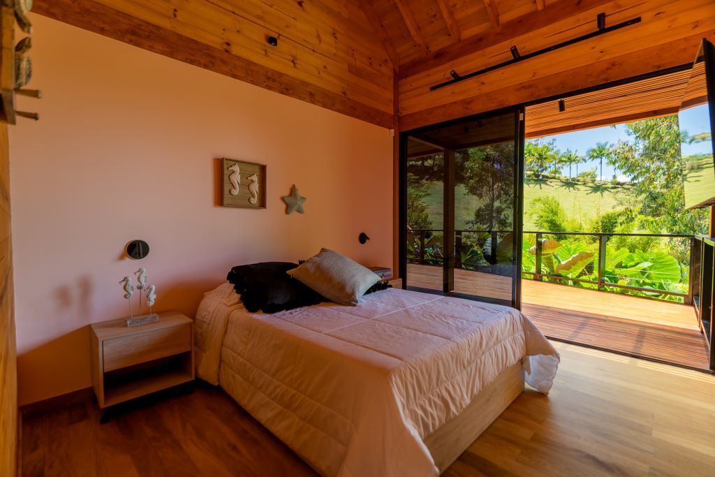 Un dormitorio con una cama grande, una mesita de noche, un reloj de pared y una decoración con estrellas. Hay una puerta corrediza de cristal que da a un área exterior con vegetación.