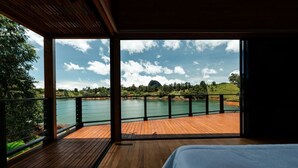 Un dormitorio con terraza de madera y vistas a un lago y colinas.