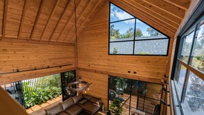 Un interior espacioso de madera con un techo alto, ventanas grandes y una zona de estar acogedora.