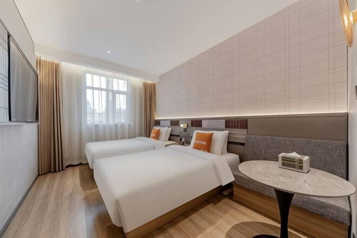 A hotel room with two beds, a round table, and a TV.