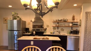A modern kitchen with a central island, a dining table with chairs, and a chandelier. - Charming cottage in scenic Seattle with AC, WiFi, and all the comforts of home. (Seattle)