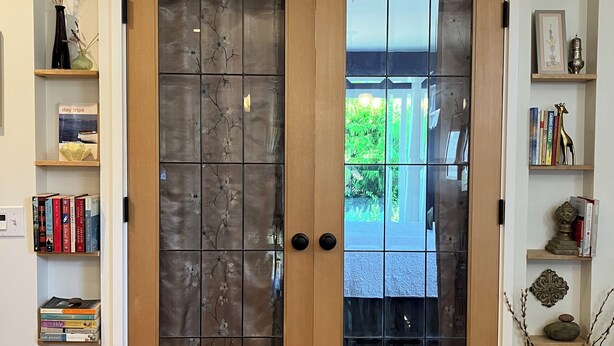 A wooden door with glass panels, flanked by shelves with books and decorative items. - Charming cottage in scenic Seattle with AC, WiFi, and all the comforts of home. (Seattle)