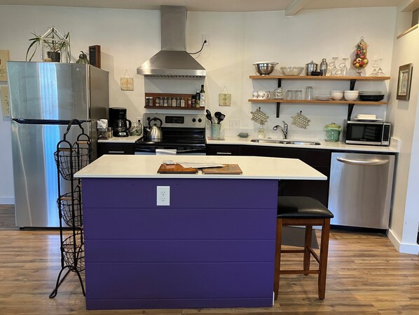 A modern kitchen with a central island, stainless steel appliances, and wooden flooring. - Charming cottage in scenic Seattle with AC, WiFi, and all the comforts of home. (Seattle)
