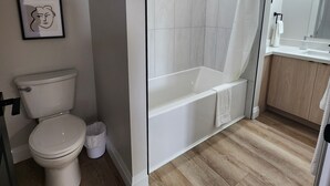 A modern bathroom with a toilet, shower, and bathtub.