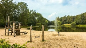 Ein Sandstrand mit einer Schaukel und einem Teich.