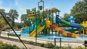 Ein Spielplatz mit Rutschen und Klettergerüsten, umgeben von einem Schwimmbecken.