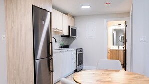 A modern kitchen with stainless steel appliances, light wood cabinets, and a round wooden table. - 1 Bedroom Unit with living space and full kitchen Prime Downtown location (Kitchener)