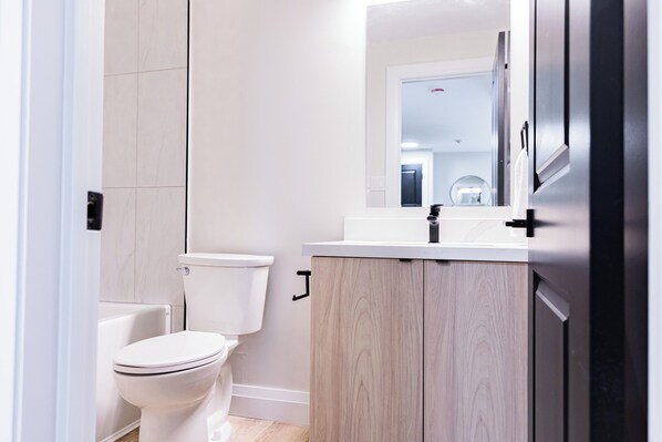 Une salle de bain moderne équipée de toilettes, d’un lavabo et d’un miroir.