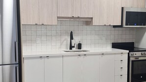 Une cuisine moderne avec des armoires blanches, un réfrigérateur en acier inoxydable, un four à micro-ondes et un four traditionnel.