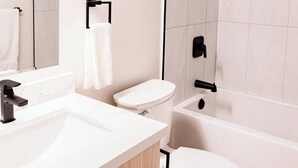 Une salle de bain moderne avec un lavabo blanc, des toilettes, une baignoire et une douche.