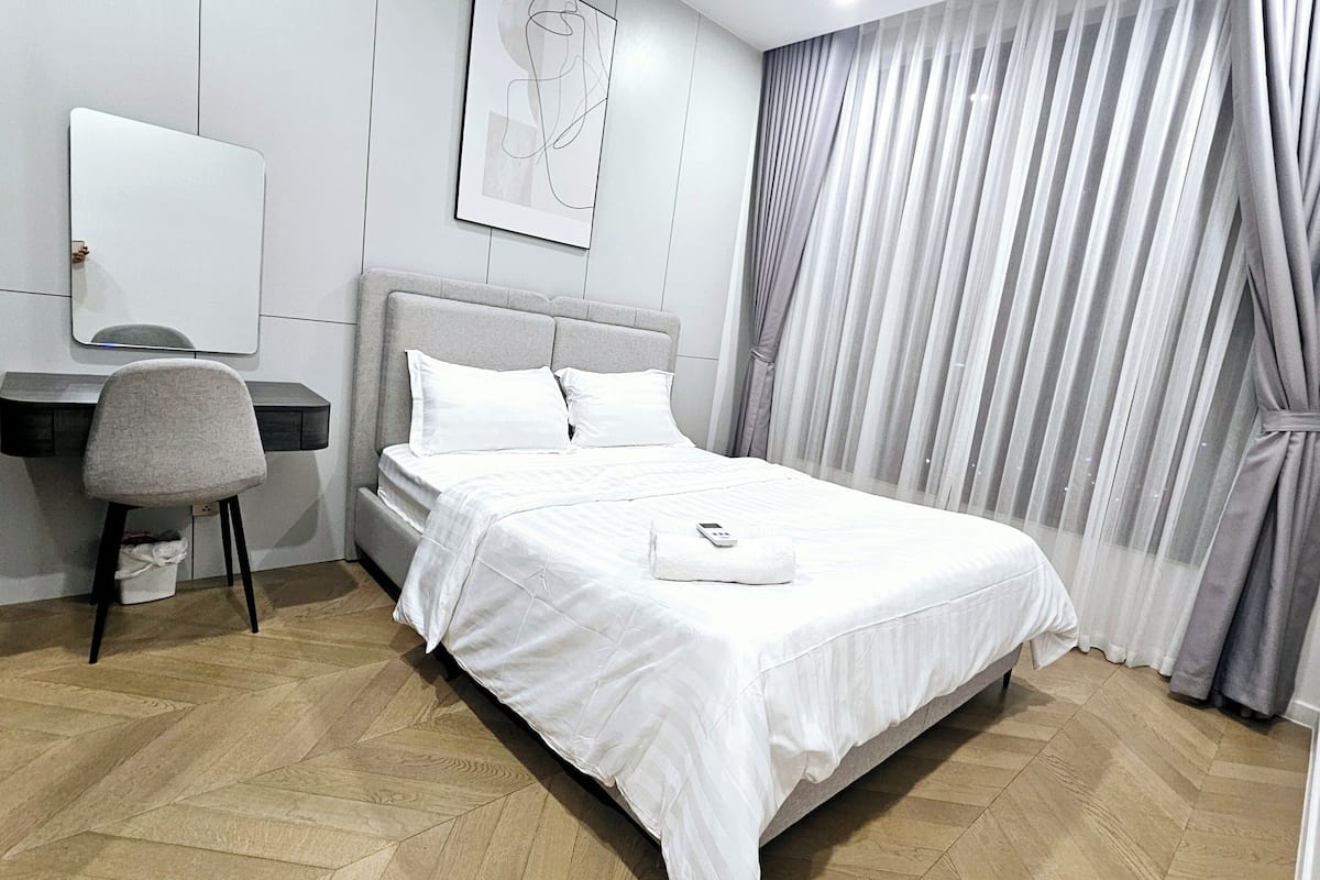 Een hotelkamer met een bed, een bureau, een stoel en een groot raam met gordijnen.