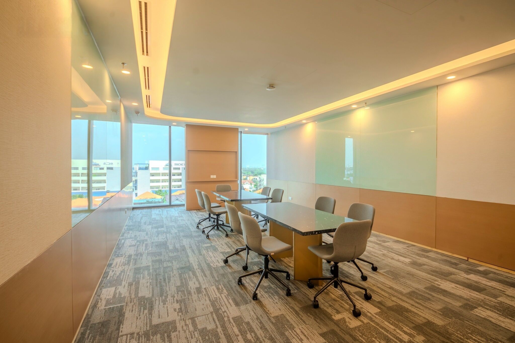 Uma sala de conferências moderna com uma mesa grande, várias cadeiras, uma tela de projetor e amplas janelas com vista para a cidade.