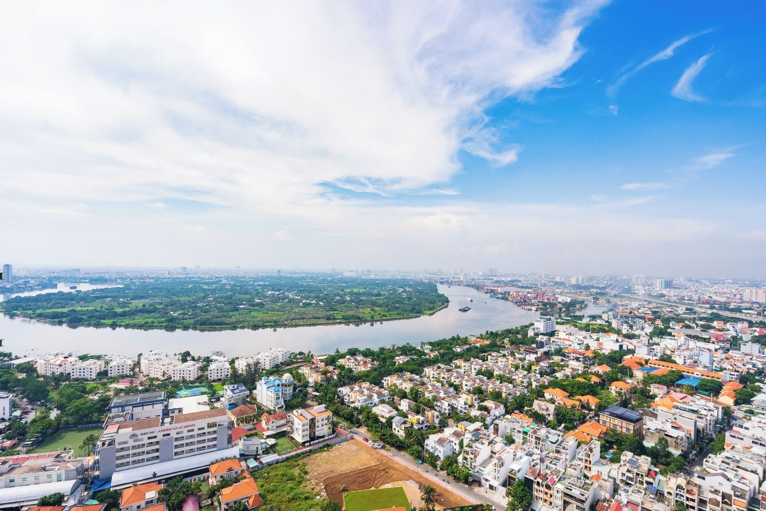 An aerial view of a city with a river, residential buildings, and a large green area.