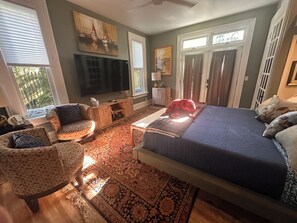 Une chambre à coucher avec un grand lit, une télévision, un fauteuil et un tapis.