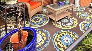 Ein überdachter Patio-Bereich mit Ziegelwänden, Deckenventilator und Gartenmöbeln.