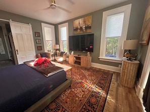 A bedroom with a bed, a television, a fireplace, and a large window.