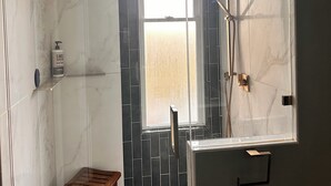 Ein modernes Badezimmer mit Dusche, Sitzbank und großem Fenster.