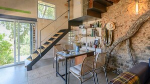 A modern interior with a staircase, dining area, and a stone wall. - El Risco del Lomero Valdelarco by Ruralidays (Huelva)