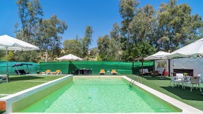 A swimming pool with a green border, surrounded by lounge chairs and umbrellas. - Casa Rural El Salao Olvera by Ruralidays (Cádiz)