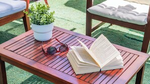 Ein Holztisch mit einem Buch, einer Sonnenbrille und einer Topfpflanze.