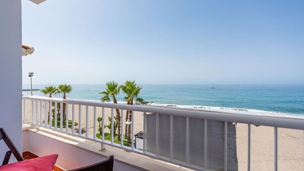 Un balcon avec vue sur une plage et l’océan.