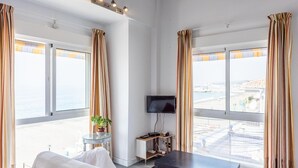 Une chambre d’hôtel avec de grandes fenêtres, un téléviseur à écran plat, une petite table avec une plante et un lit.