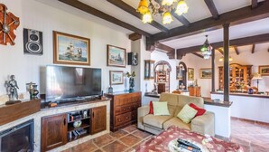 Een knusse woonkamer met een televisie, houten meubels en diverse decoraties.