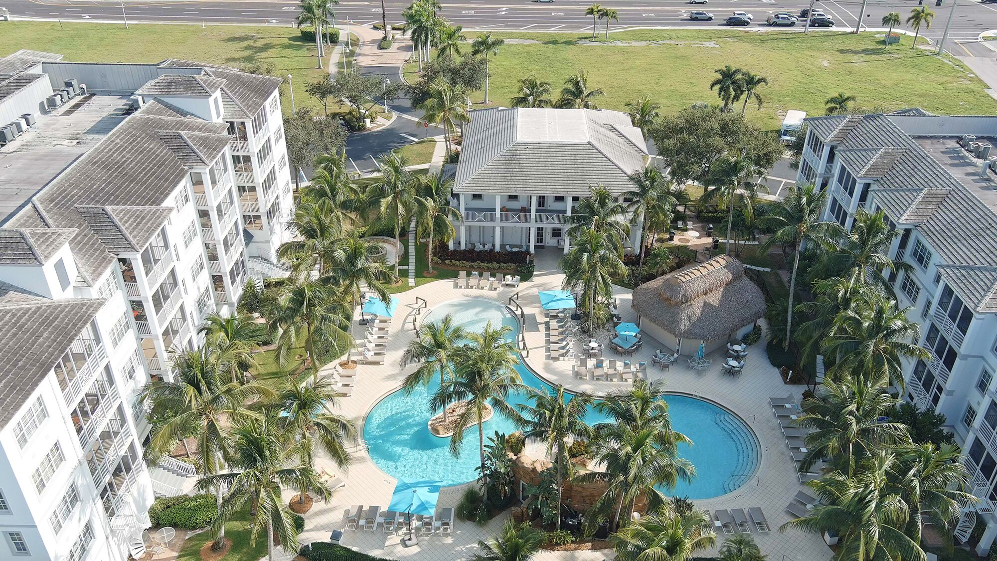 A hotel with a central pool, multiple balconies, and palm trees.