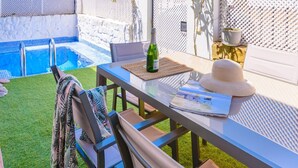 A poolside area with a table, chairs, a bottle of wine, and a hat. - El Campanario El Bosque by Ruralidays (Cádiz)