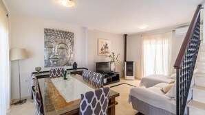 A modern living room with a dining area, a flat-screen TV, and a staircase. - El Campanario El Bosque by Ruralidays (Cádiz)