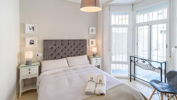 A bedroom with a tufted headboard, a bed with white linens, bedside lamps, and framed pictures on the walls. - El Campanario El Bosque by Ruralidays (Cádiz)