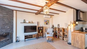 Un salon avec une cheminée, un téléviseur, un meuble de rangement en bois et un fauteuil.
