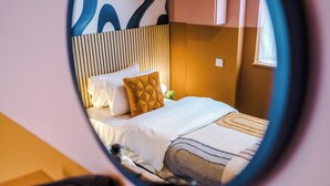 A bedroom with a bed, pillows, a nightstand, and a mirror reflecting the room. - Modern 4-Bedroom in Manchester (Salford)