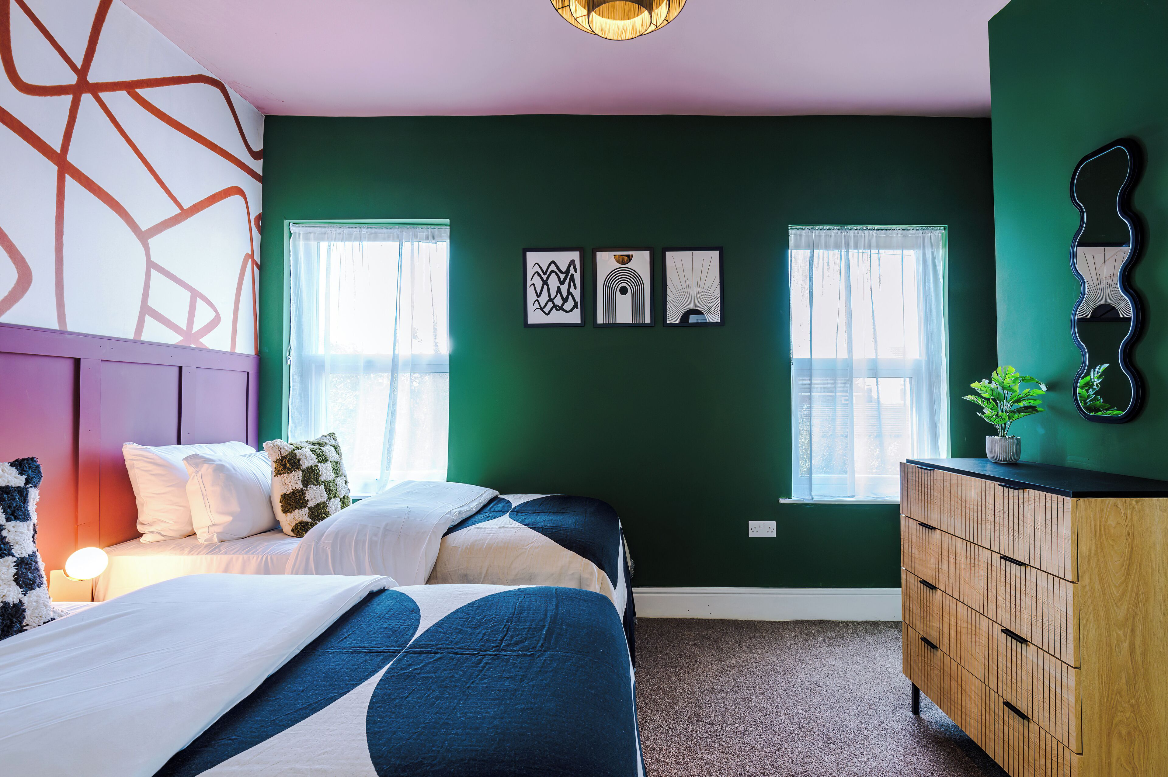 Une chambre à coucher avec un lit, une commode et des œuvres d’art accrochées au mur.