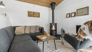 A modern living room with a sectional sofa, a wooden coffee table, a black armchair, a fireplace with a chimney, and a framed picture on the wall.