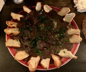A plate of beef stew with bread on a red plate. - Quinta de Cypriano - Wine & Nature (Ponte da Barca)