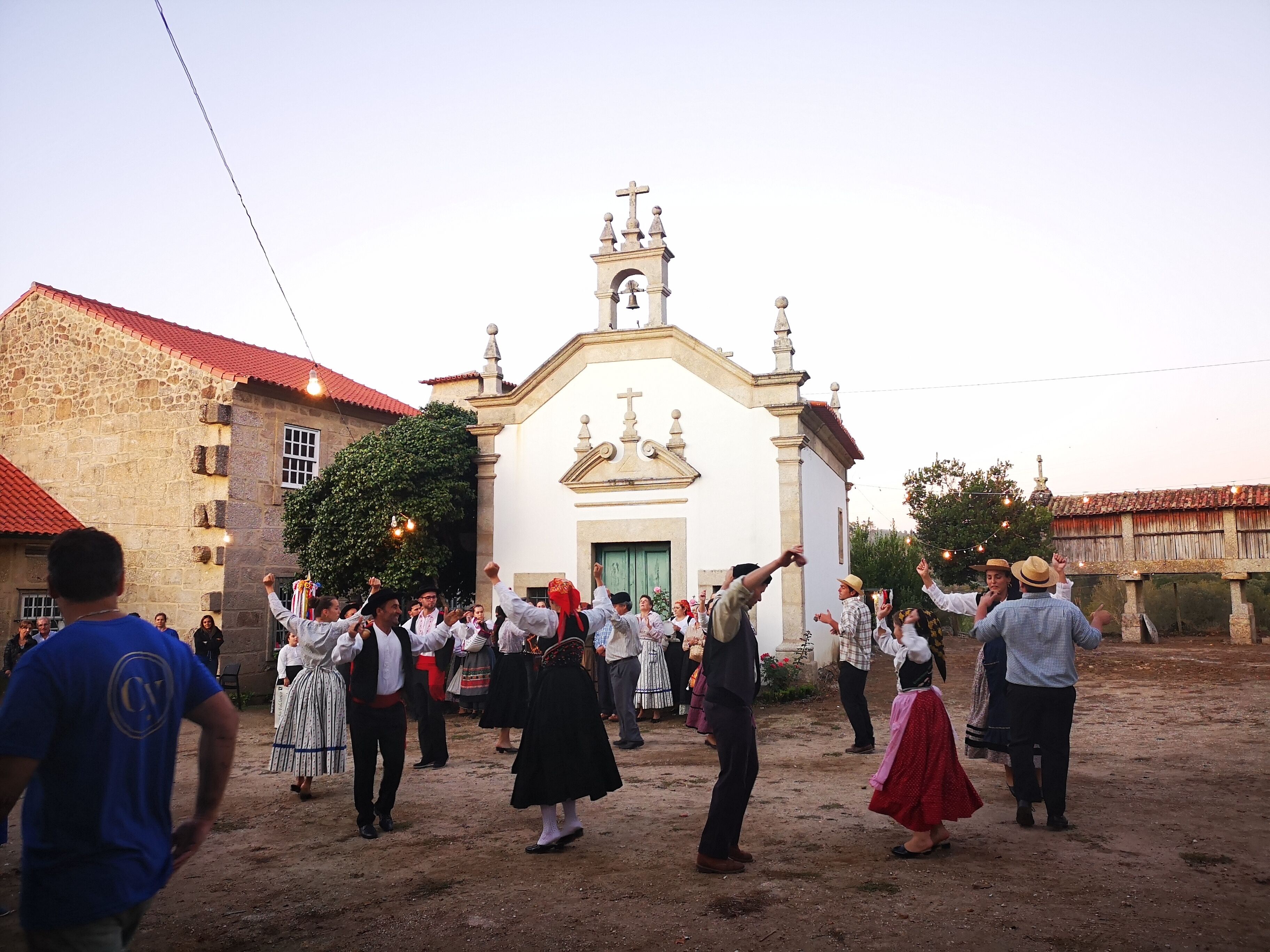 A group of people dancing in front of a church with a bell tower.