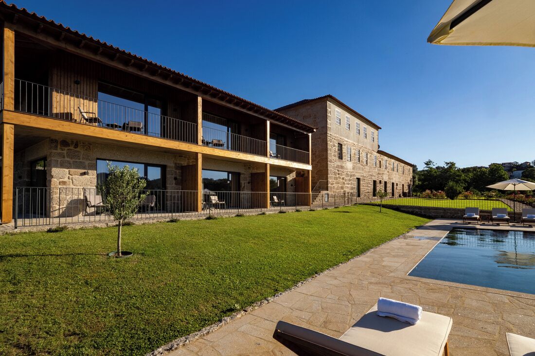 A two-story building with a stone facade, a swimming pool, and outdoor seating.