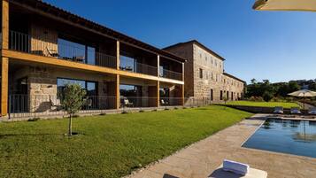 A two-story building with a stone facade, a swimming pool, and outdoor seating.