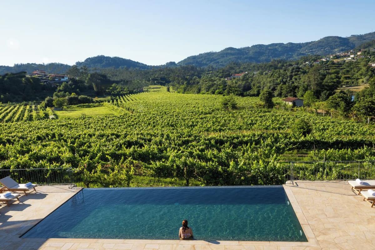 A pool with a view of a vineyard and hills in the background.