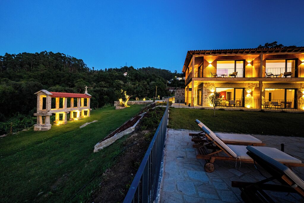 Un edificio de dos pisos con fachada de piedra y techo rojo, iluminado con luz cálida.